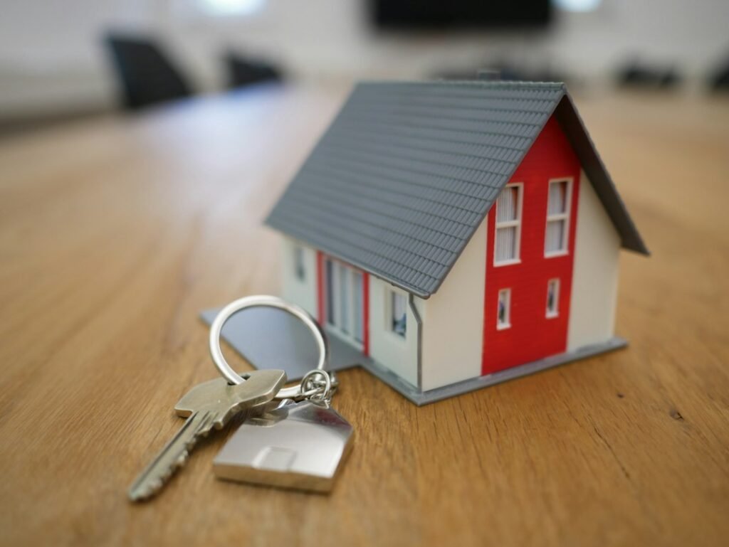 Illustrative image of house keys next to a miniature house for rent-versus-buy article